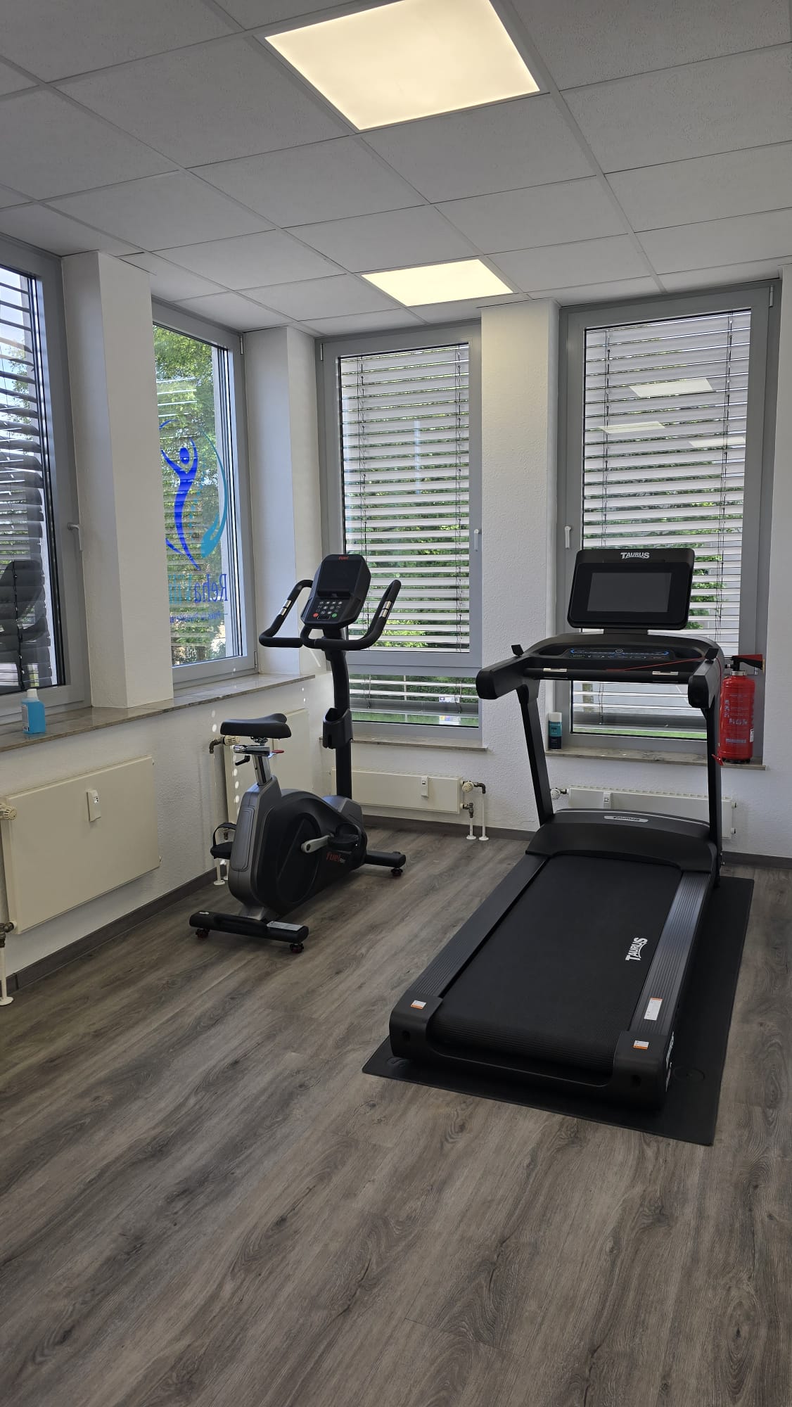 Heller Trainingsraum mit Ergometer und Laufband.